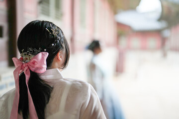 In Seoul in June 2025, two Korean women in their twenties wearing pink and sky-blue hanbok stand in...