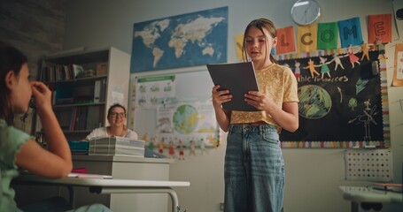 Primary School Girl Holding Notebook Speaking, Showcasing Knowledge of Ecology in Front of Classmates and Teacher. Smart Pupil Presenting Homework During Environmental Science Lesson. Dolly Shot.