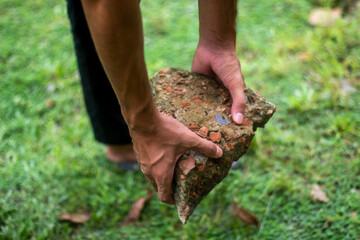 A boy holds an Old brick on the grass