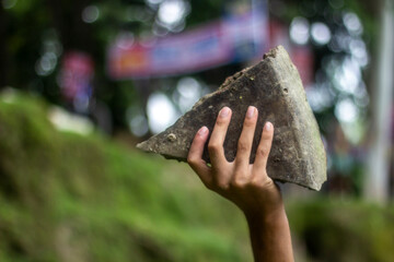 A boy holds an Old brick on the grass, and the background is blurred