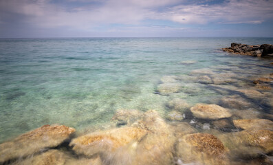 Crystal clear water gently washing over rocks on a cloudy day