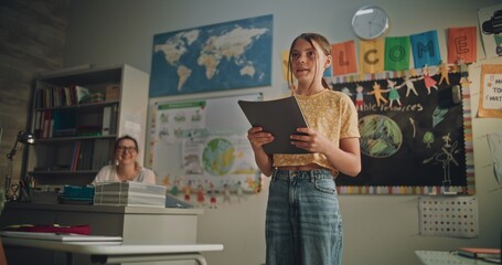 Renewable Energy Lesson: Elementary School Girl Holding Notebook Speaking, Giving Presentation on Geography in Front of Classmates and Teacher. Student Showcasing Knowledge of Ecology. Dolly Shot.