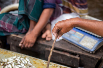 A man shows his hand on the fish table in the market