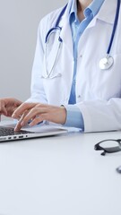 Unrecognizable doctor woman is typing on a laptop with a stethoscope, medical record, and pen on...