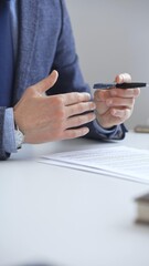 Professional businessman gesturing while discussing strategy, seated at white desk with tablet,...