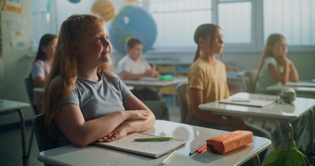 Focus on Elementary School Girl Writing in School Notebook During Geography Lesson in Modern...