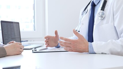 Doctor gesturing with hands while explaining diagnosis to patient during medical consultation in...