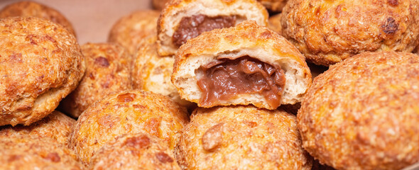 Pile of freshly baked pastries filled with rich chocolate cream. Golden brown crusts showcase crispy texture, hinting at soft, fluffy interior. Perfect for breakfast, dessert, snack, sweet treats