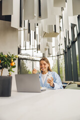 A young woman enjoys her meal while multitasking in a stylish, bright, modern and welcoming office...