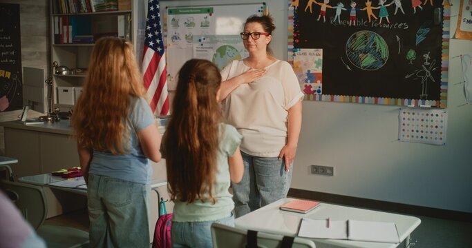 Female Teacher and Elementary School Students Standing and Singing National Anthem of the Country with Hands on Their Hearts Before Ecology Lesson. Development of Patriotism in Younger Generation.