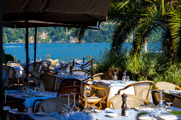Cernobbio, Lake Como, Lombardy - July 7, 2025: View of Lake Como from a restaurant in Cernobbio. Tables are set ready to welcome tourists.