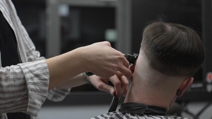 Professional barber cutting client's hair with electric clipper, working precisely in contemporary...
