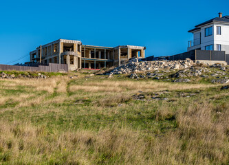 An unfinished house on a hilltop on a summer day.