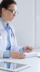 Adult doctor woman completing healthcare paperwork, clipboard positioned near laptop and...