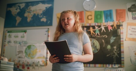 Renewable Energy Lesson: Elementary School Girl Holding Notebook Speaking, Giving Presentation on...