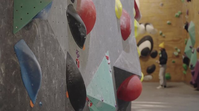 Closeup of climbing holds on gray wall in the gym, showcasing full frame of artificial rock climbing wall with various colorful handles for climbing
