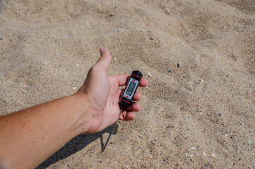 Hand Holding Digital Thermometer Measuring Sand Temperature