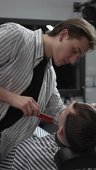 Naklejka premium Professional barber trimming customer's hair with electric clipper, focusing on precise nape grooming within contemporary barbershop interior design