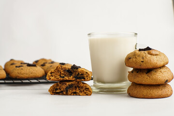 Chocolate chunk cookies served with milk in a glass on white table, cozy and minimal style.