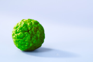 Fresh kafir lime with textured surface, showcasing its vibrant green color against soft background. This unique fruit adds distinct flavor to various dishes and beverages