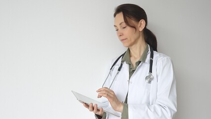 Headshot of a doctor woman wearing white medical coat over green blouse, stethoscope, is reviewing...