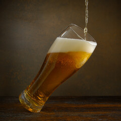 Beer. Jet of beer is poured into a beer glass, causing a lot of bubbles and foam