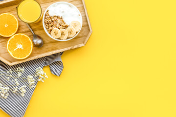 Healthy granola with banana and orange juice for colorful breakfast on yellow background top view mock-up
