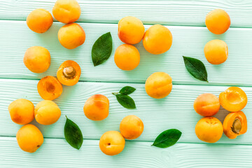 Apricots and leaves pattern on green wooden background top view