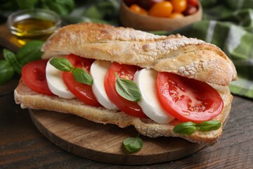 Tasty sandwich with mozzarella cheese, tomatoes and basil on wooden table, closeup