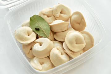 A Close-Up View of Soft and Delicate Dumplings Perfectly Arranged with a Bay Leaf for Flavor Enhancement in a Transparent Container