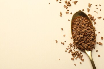 Spoon with granulated instant coffee on beige background, top view. Space for text