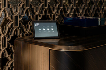 Smart home hub with weather information displayed (12:28, 15°) showing forecasts, resting on a...