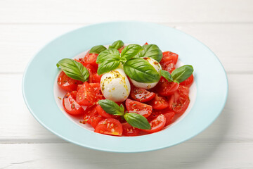 Tasty salad Caprese with mozzarella, tomatoes, basil and spices on white wooden table, closeup