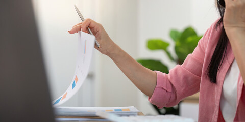 Work from home Close-up of woman reviewing documents while on a phone call.