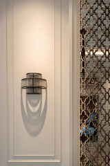 Modern wall sconce with concentric metal rings casting a decorative shadow on a white paneled wall...
