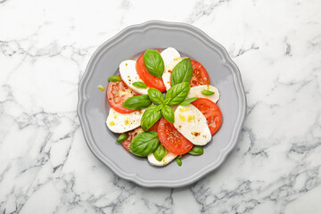 Tasty salad Caprese with mozzarella, tomatoes, basil and spices on white marble table, top view