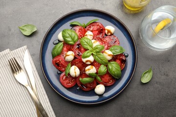 Tasty salad Caprese served with balsamic vinegar on grey table, flat lay