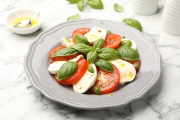 Tasty salad Caprese with mozzarella, tomatoes, basil and spices on white marble table, closeup