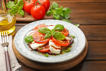 Tasty salad Caprese with mozzarella, tomatoes, basil and spices on wooden table, closeup