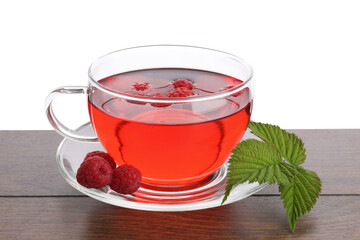 Tasty raspberry tea, berries and leaves on wooden table against white background