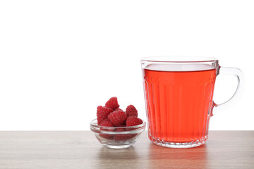 Aromatic raspberry tea in glass cup and berries on wooden table against white background
