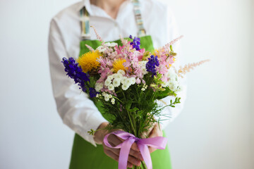 Florist with beautiful bouquet of flowers near white wall indoors, closeup