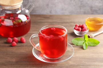 Aromatic raspberry tea, berries, mint and honey on wooden table, closeup