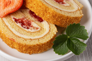 Two pieces of strawberry roll on a white plate