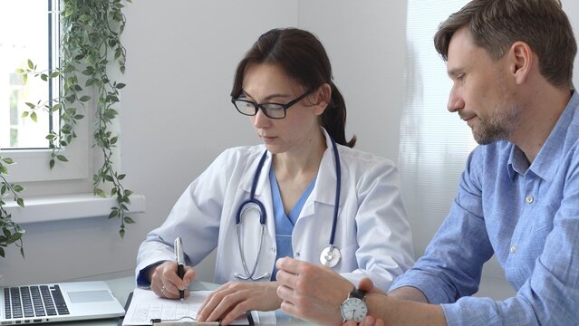 Female doctor consulting with patient in medical office, using laptop to provide healthcare advice and support while discussing treatment options in a professional setting. Medicine concept