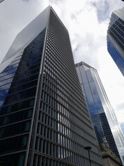 Obraz premium An ultra-modern skyscraper reaching into the cloudy skies in London. This shows a generic, modern, glass skyscraper among clouds and similar buildings.