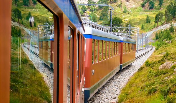 View from the window of a historic electric railcar as it descends from Gornergrat to Zermatt (Valais, Switzerland). Train of the famous cog railway on the route through impressive natural surrounding