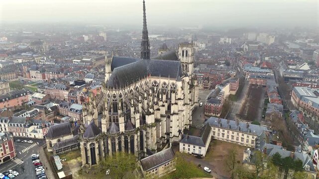 Aerial view of the eastern end of Amiens Cathedral with detailed flying buttresses and apse surrounded by the urban landscape of Amiens France on a cloudy day 