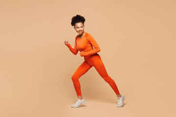 Full body side profile view young fitness trainer instructor sporty woman sportsman wears orange...