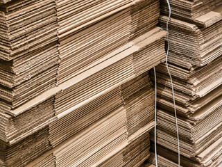 Stacks of cardboard sheets organized in a workshop for packaging and shipping materials near a busy...
